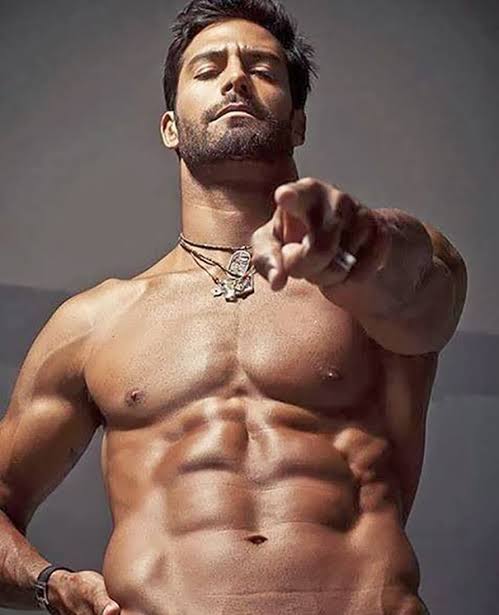 Shirtless man with defined abs pointing at the camera.