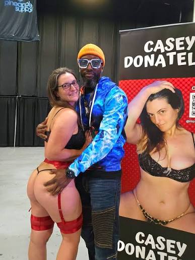 Casey Donatel in red lingerie posing with a man.