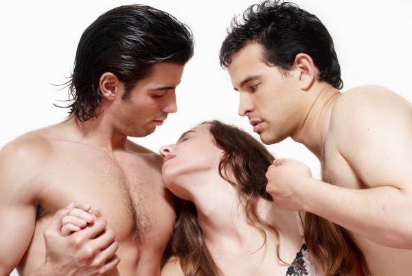 Two shirtless men and a woman in an intimate pose.
