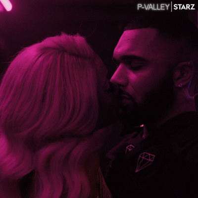 A man and woman lean in close under magenta light.