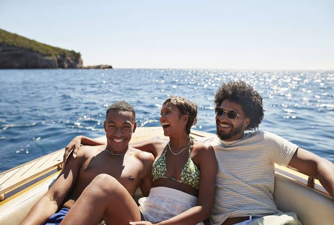 Three happy friends laughing together on a boat at sea.