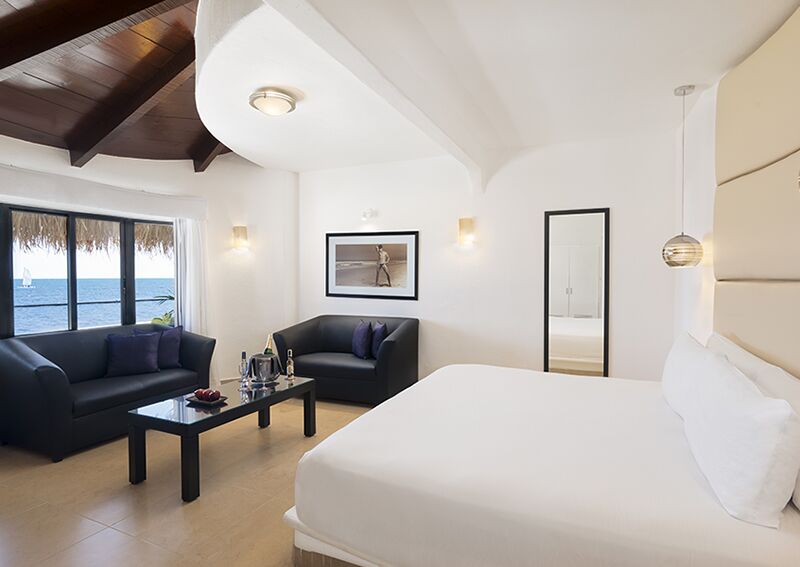 Desire Riviera Maya Jacuzzi Room Ocean View with king bed, lounge seating, and Caribbean views