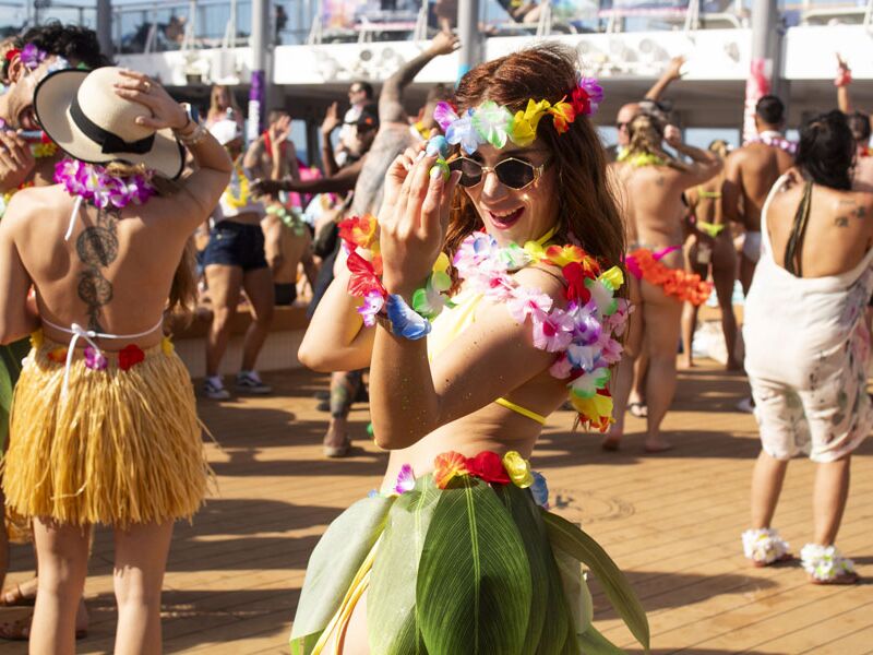 Guests in leis and grass skirts at a Luau Party theme event on an earlier Temptation cruise